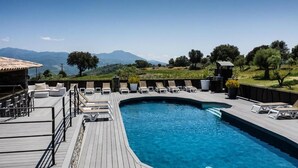 Ein Pool mit Liegestühlen und einer Terrasse mit Blick auf eine gebirgige Landschaft.