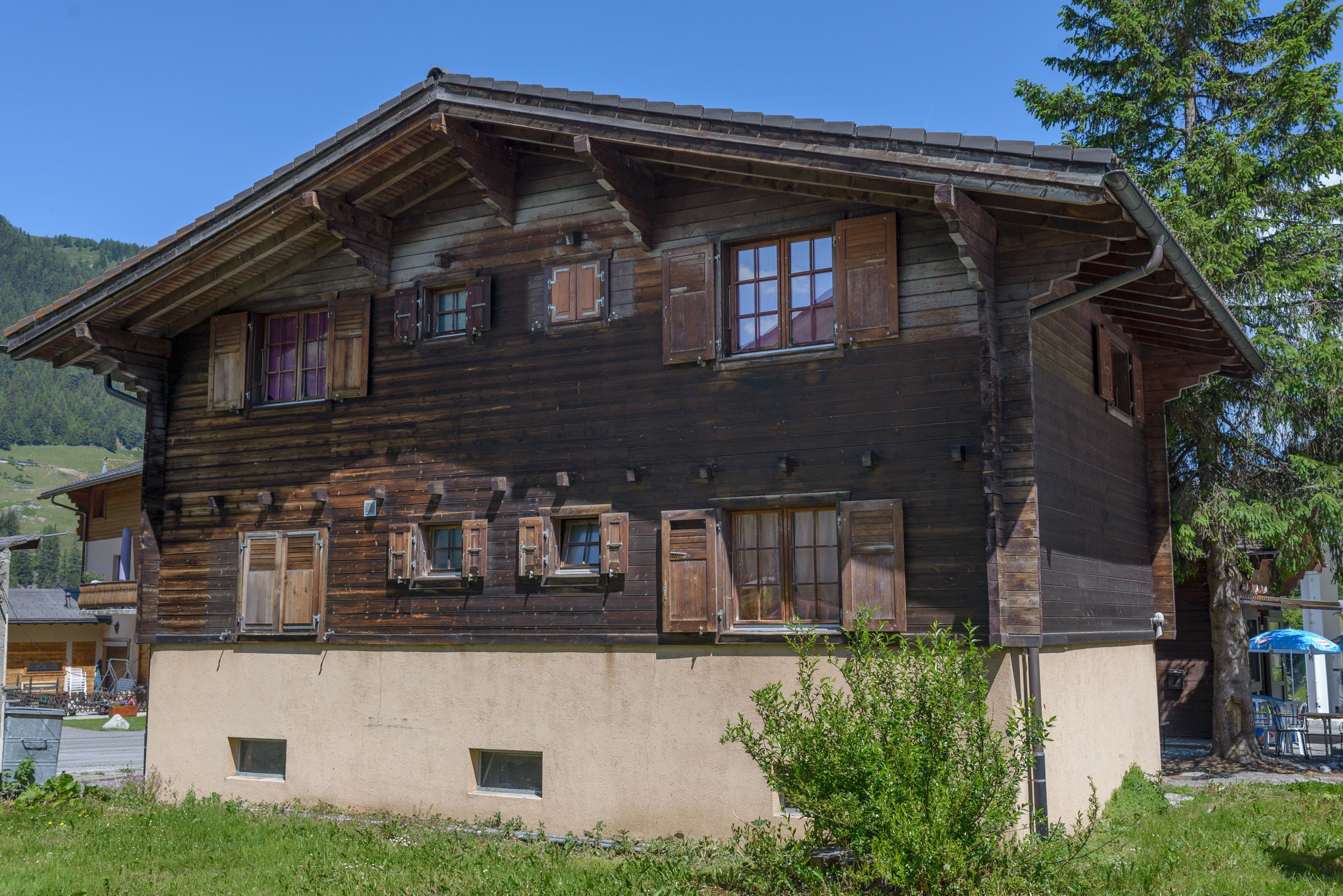 Una casa a due piani in legno con diverse finestre e un balcone.