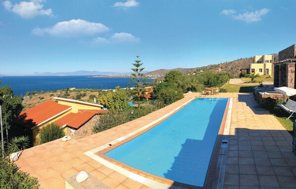 A swimming pool with a view of the sea, surrounded by a patio area with outdoor furniture. - Beach front home in Perdika (Perdika)