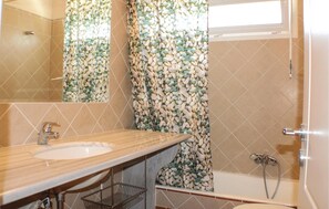 A bathroom with a wooden vanity, a mirror, a bathtub, and a shower. - Beach front home in Perdika (Perdika)