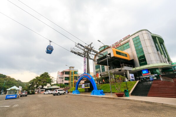 A modern building with a curved facade, a cable car system, and a prominent blue archway. - Ruby Hotel (Vung Tau)