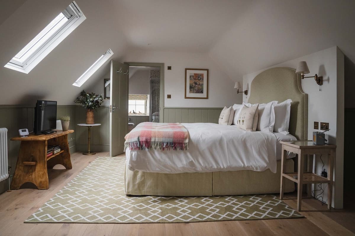 A bedroom with a bed, bedside tables, a desk, a mirror, and a window.
