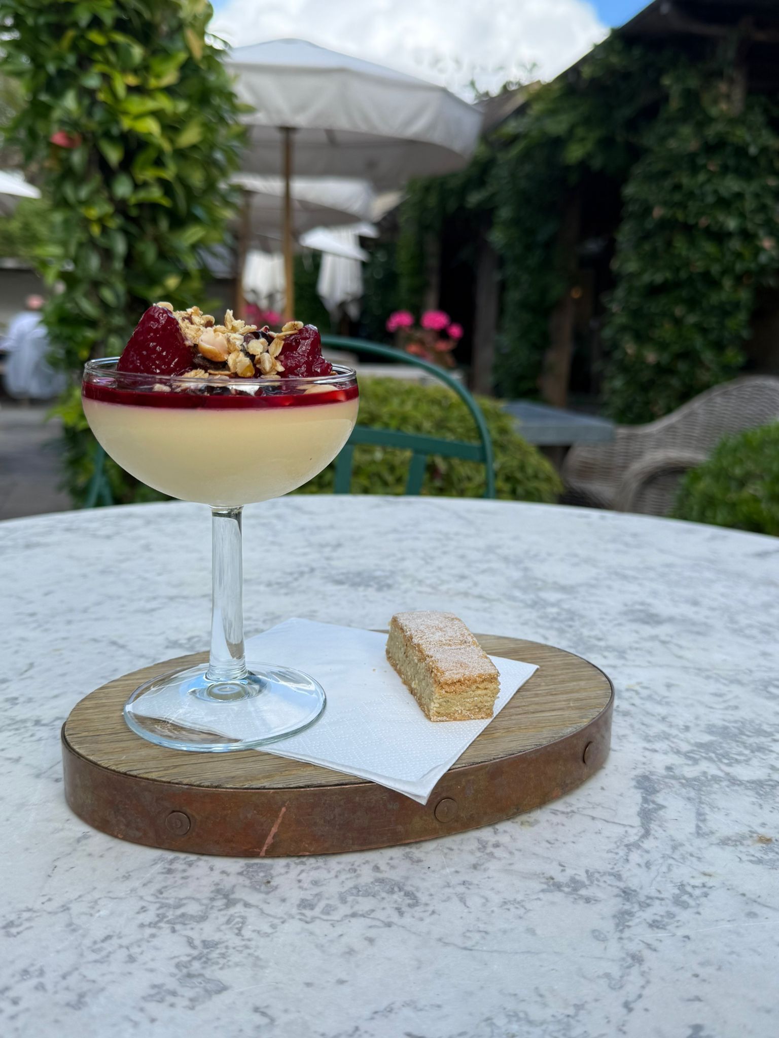Ein Dessert im Glas auf einer Holzbrettchen, daneben ein Stück Kuchen.