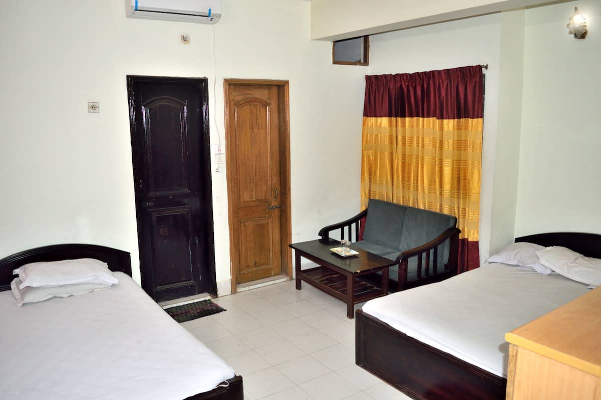 A room with two beds, a wooden door, a television, and a window with curtains.