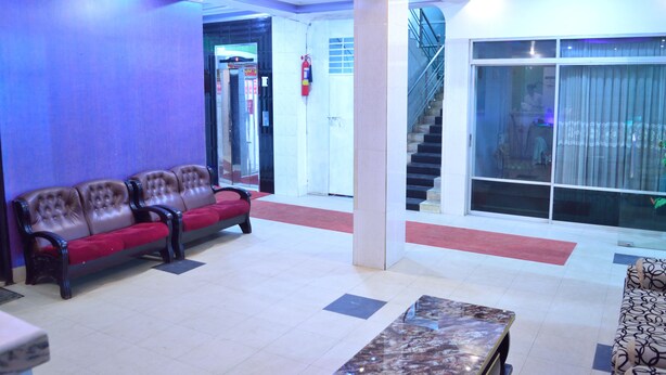Eine Lobby mit rotem Teppich, einem Marmortisch und einer Treppe.