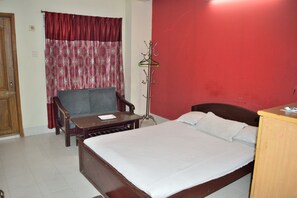 A bedroom with a bed, a chair, a desk, and a coat rack. - Sea Breeze Resort (Cox's Bazar)