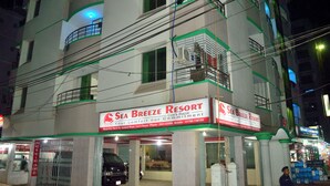 Ein mehrstöckiges Gebäude mit einem Schild für "Sea Breeze Resort", das es als Hotel kennzeichnet. Es gibt mehrere Balkone und einen verschlossenen Eingang.