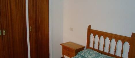 A bedroom with a wooden bed, a nightstand, and a wardrobe.