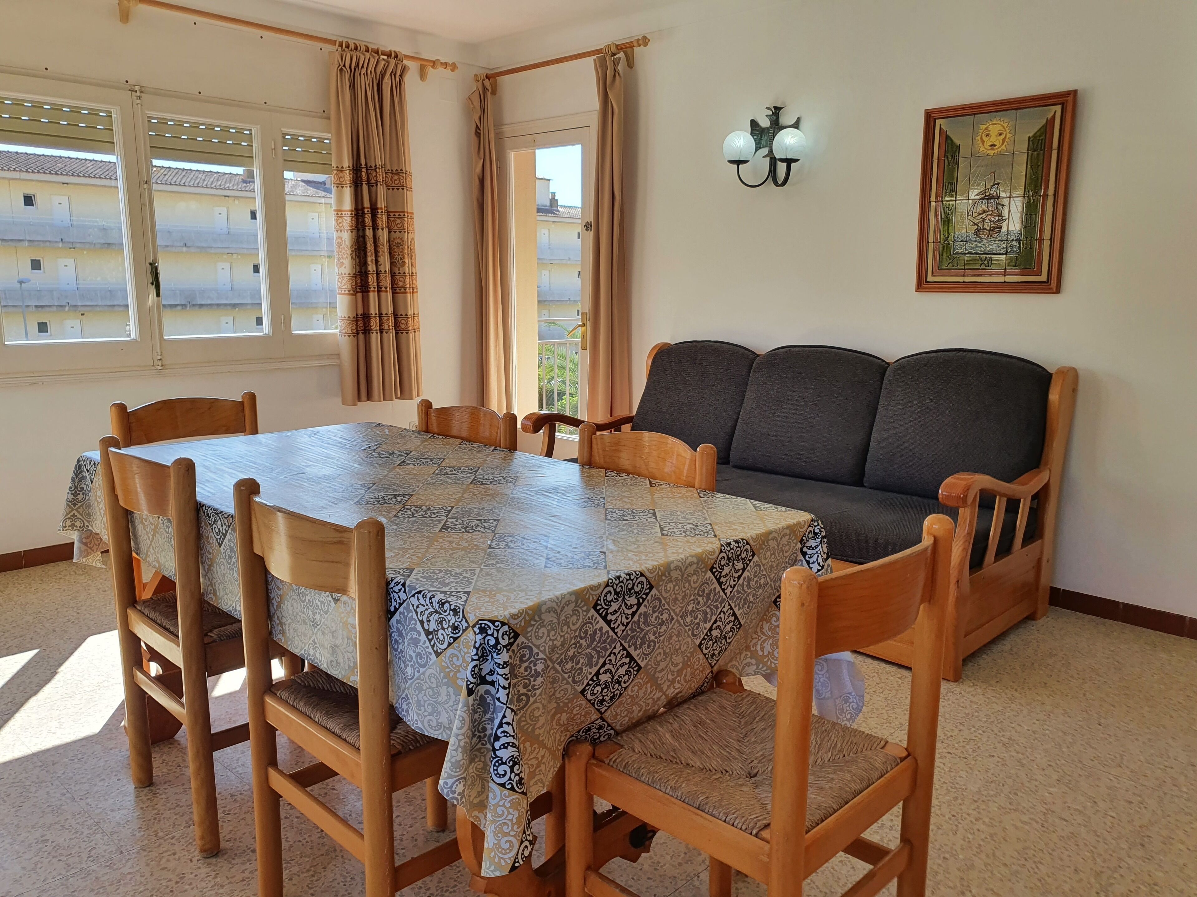 Un coin repas avec une table recouverte d’une nappe à motifs, entourée de chaises en bois.