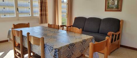 Un coin repas avec une table recouverte d’une nappe à motifs, entourée de chaises en bois.