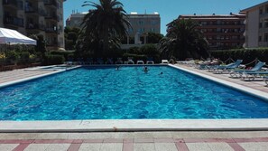 Una piscina al aire libre de temporada, sombrillas, tumbonas