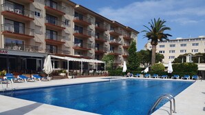 A swimming pool with lounge chairs and umbrellas, a bar, and a multi-story building with balconies. - Payet Apartments 4-6 Personas (Torroella de Montgrí)