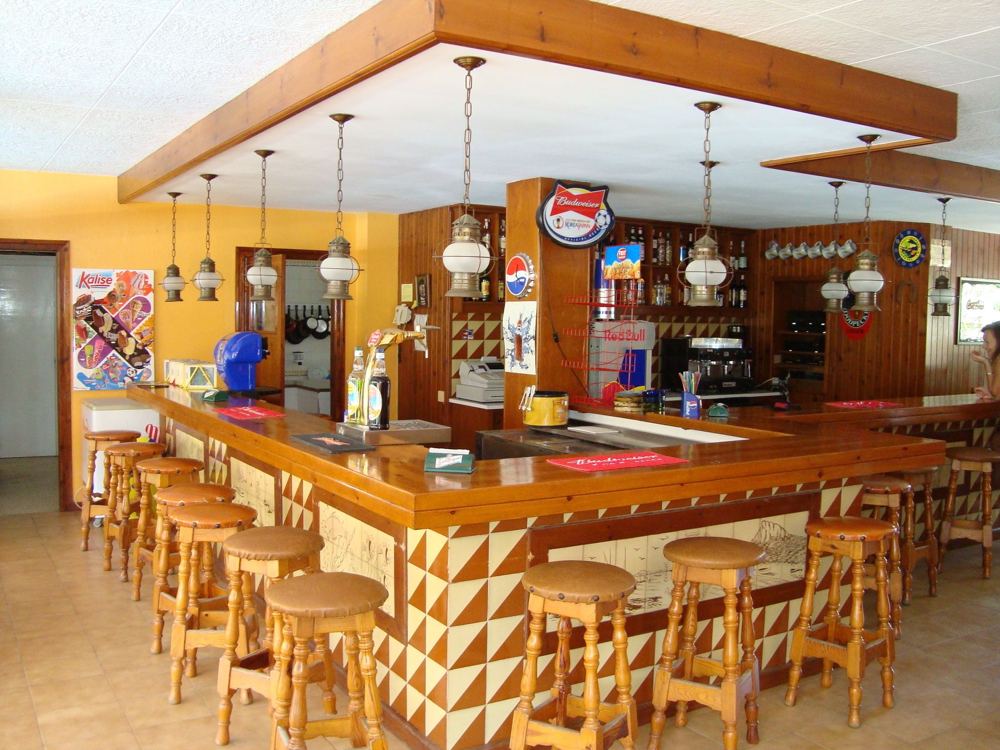 A bar area with wooden stools, a counter, and various bottles and decorations.
