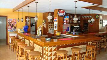 Un espace bar avec des tabourets en bois, un comptoir et diverses bouteilles et décorations.