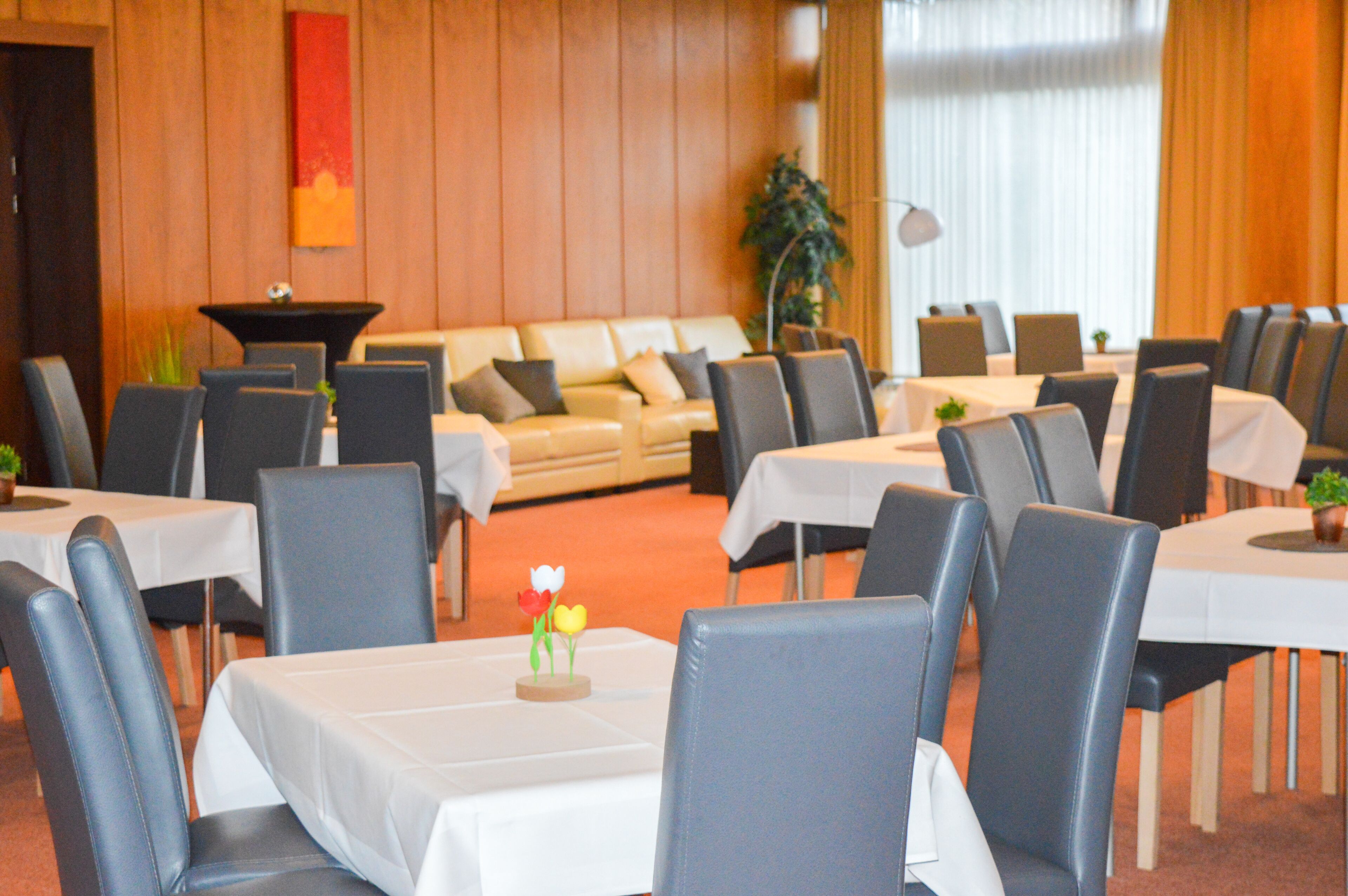 A dining area with tables and chairs, a sofa, and a plant.