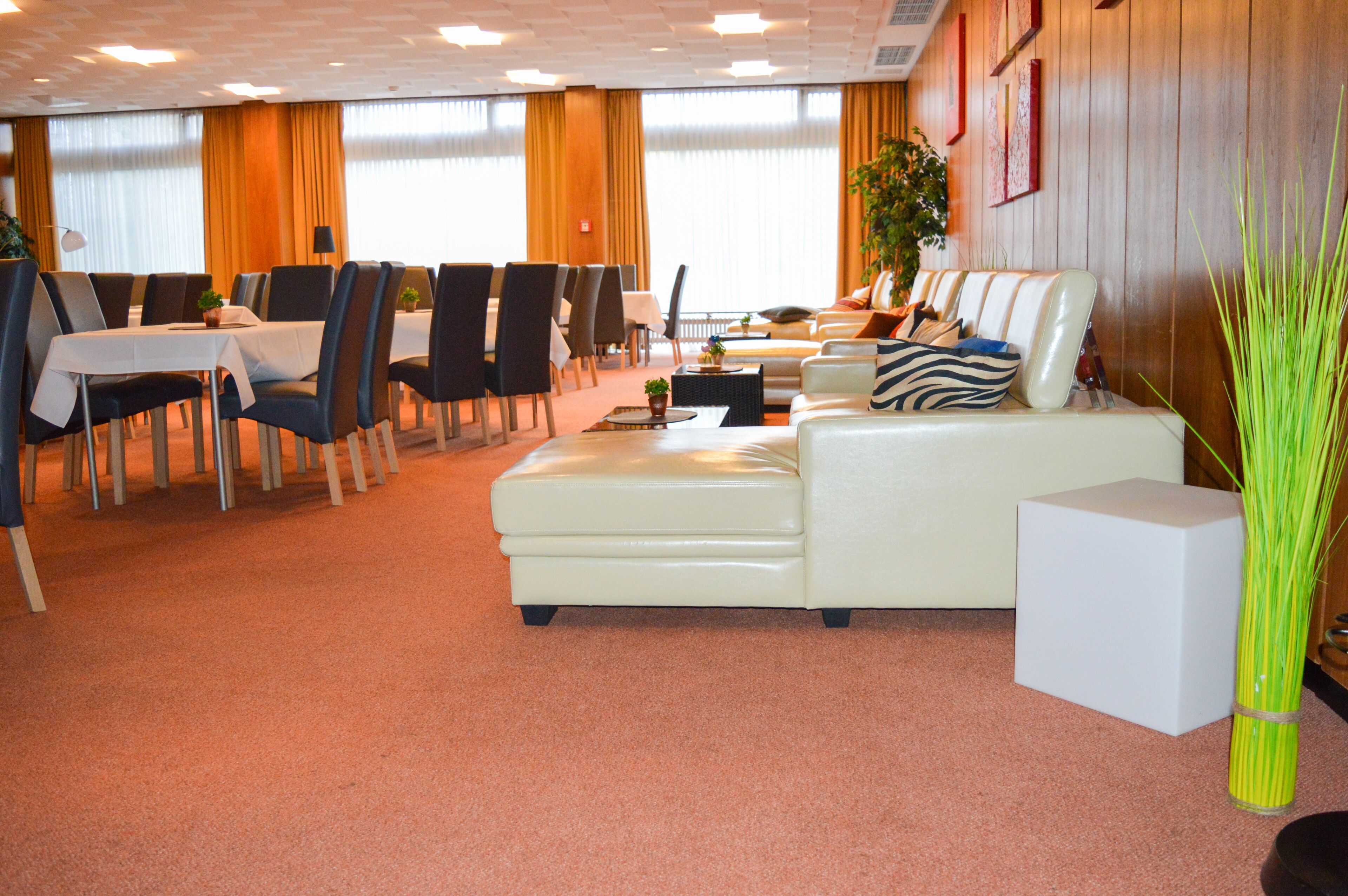 Eine Hotelhalle mit Essbereich, einer Couch und einer großen Pflanze.