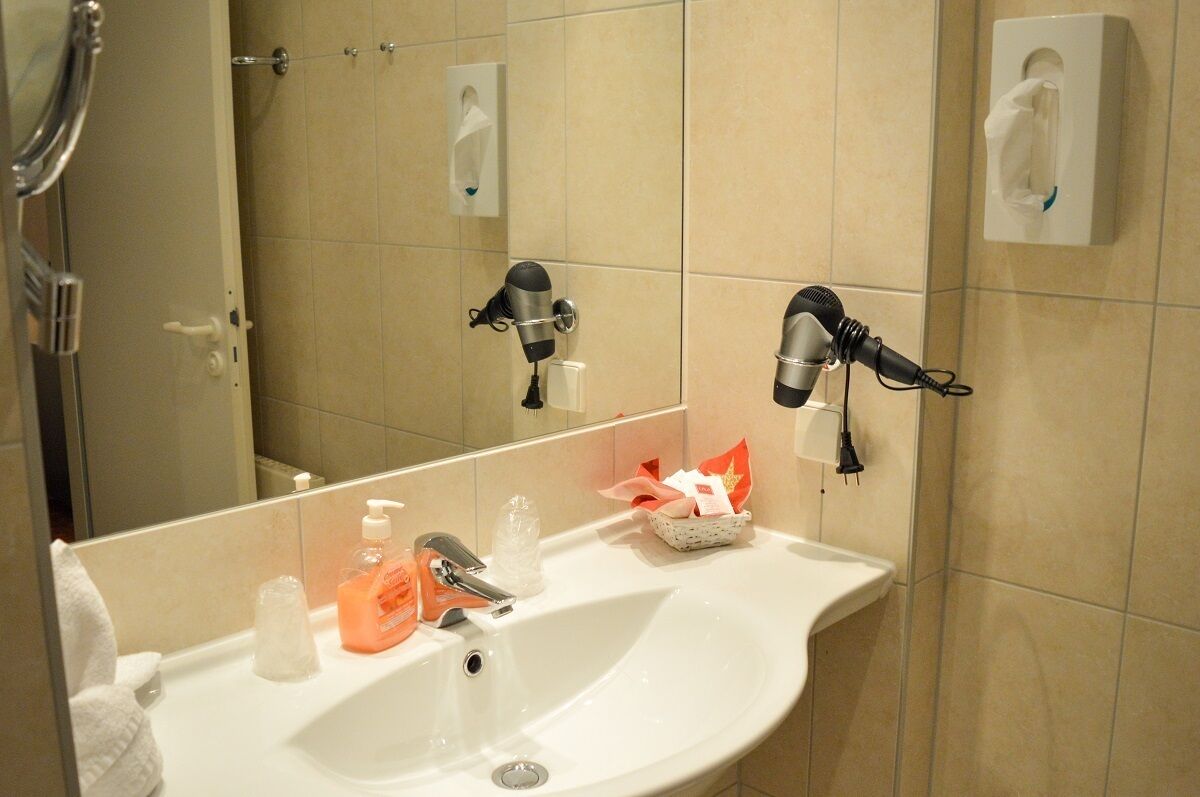 Ein Badezimmer mit Waschbecken, Spiegel und zwei an der Wand befestigten Haartrocknern.