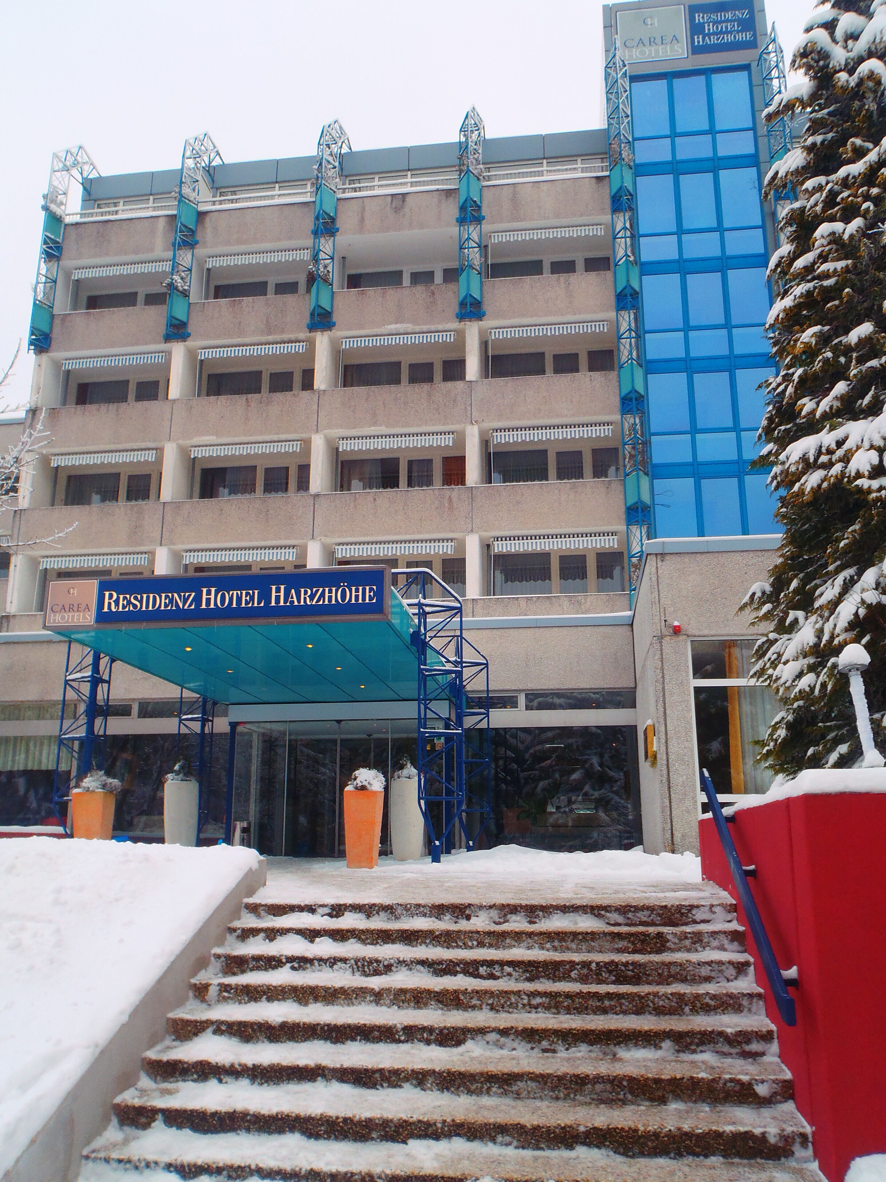 Entrada de hotel com toldo azul e escadaria que leva ao acesso.