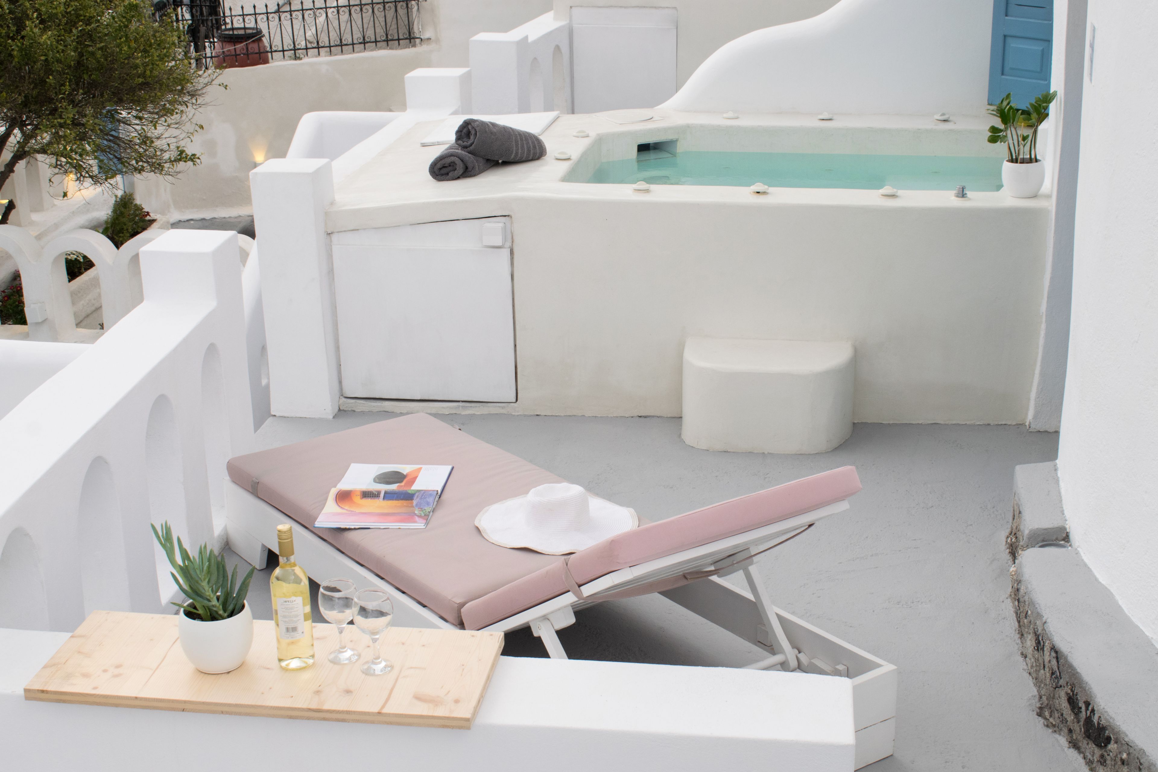Eine Dachterrasse mit Whirlpool, Liegestühlen, einem kleinen Tisch mit einer Pflanze, Weingläsern und einer Weinflasche.