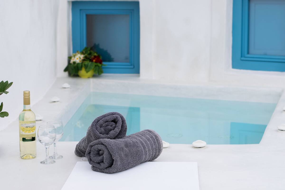 Un área de spa con piscina, toallas, vino y copas.