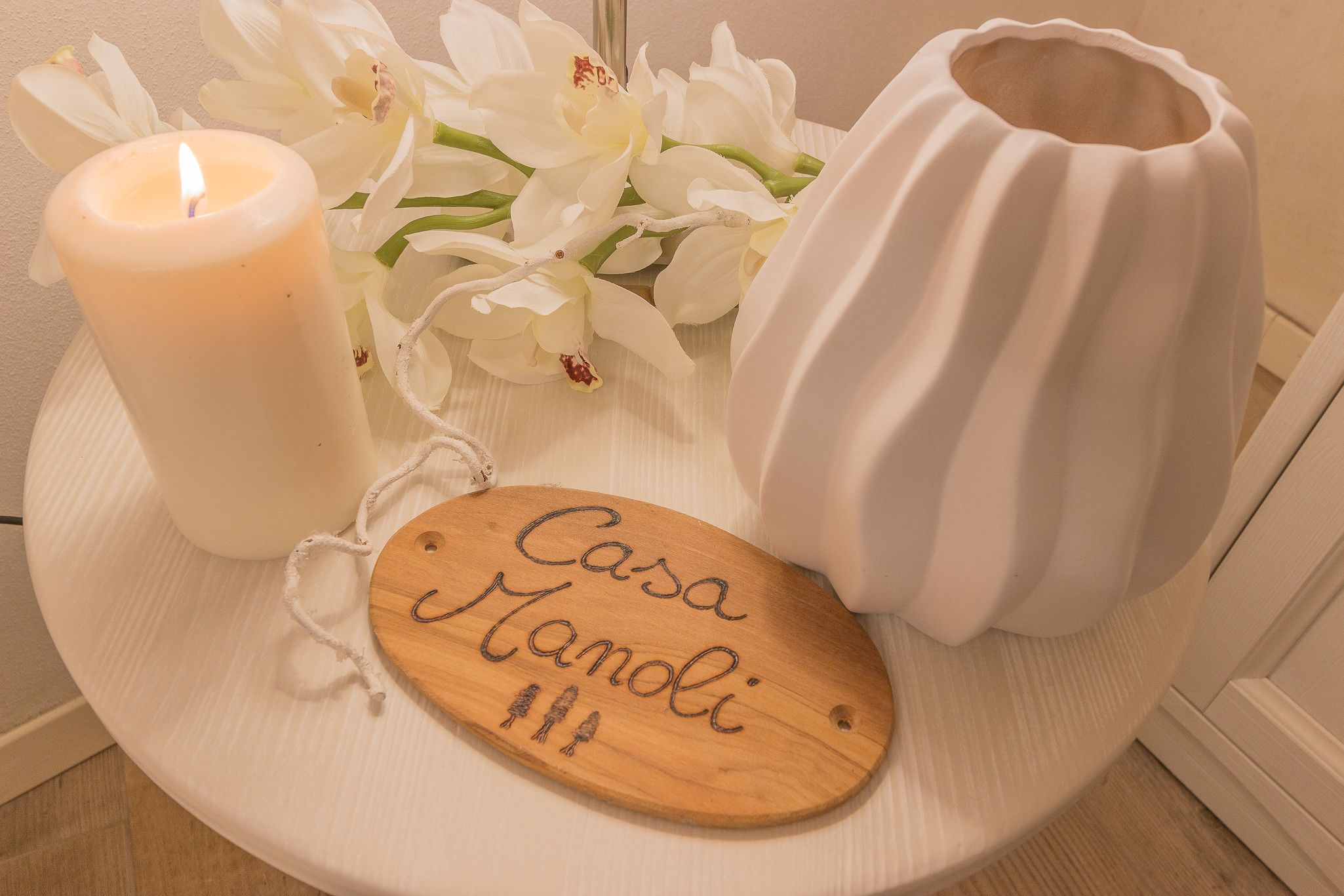 Une bougie, des fleurs blanches et une plaque nominative en bois, le tout disposé sur un plateau.