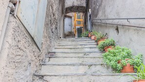 A narrow stone staircase with potted plants on the sides, leading to a door at the top. - Casa Manoli Varenna (Varenna)