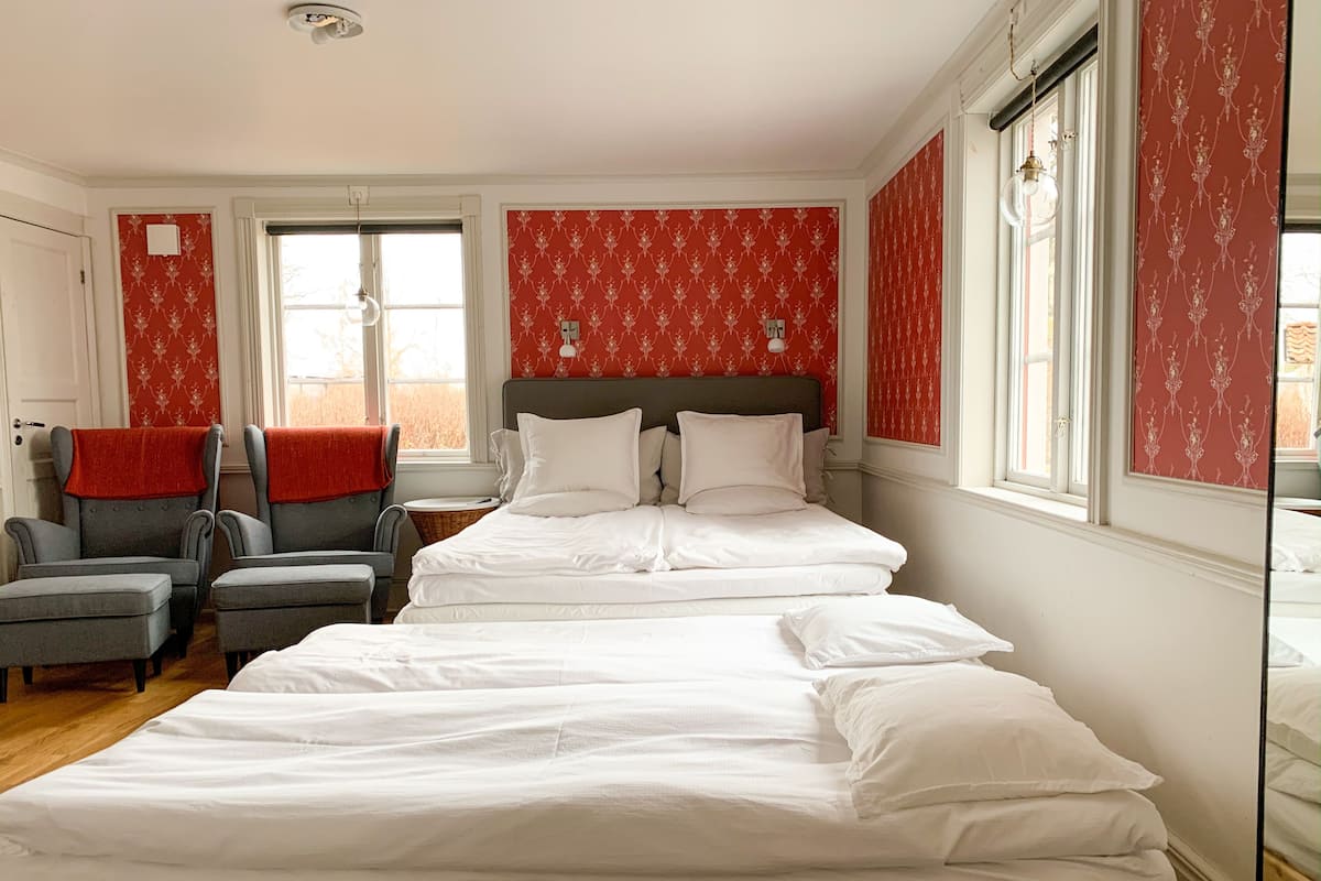 Une chambre à coucher avec un grand lit, deux fauteuils, une petite table et un miroir.