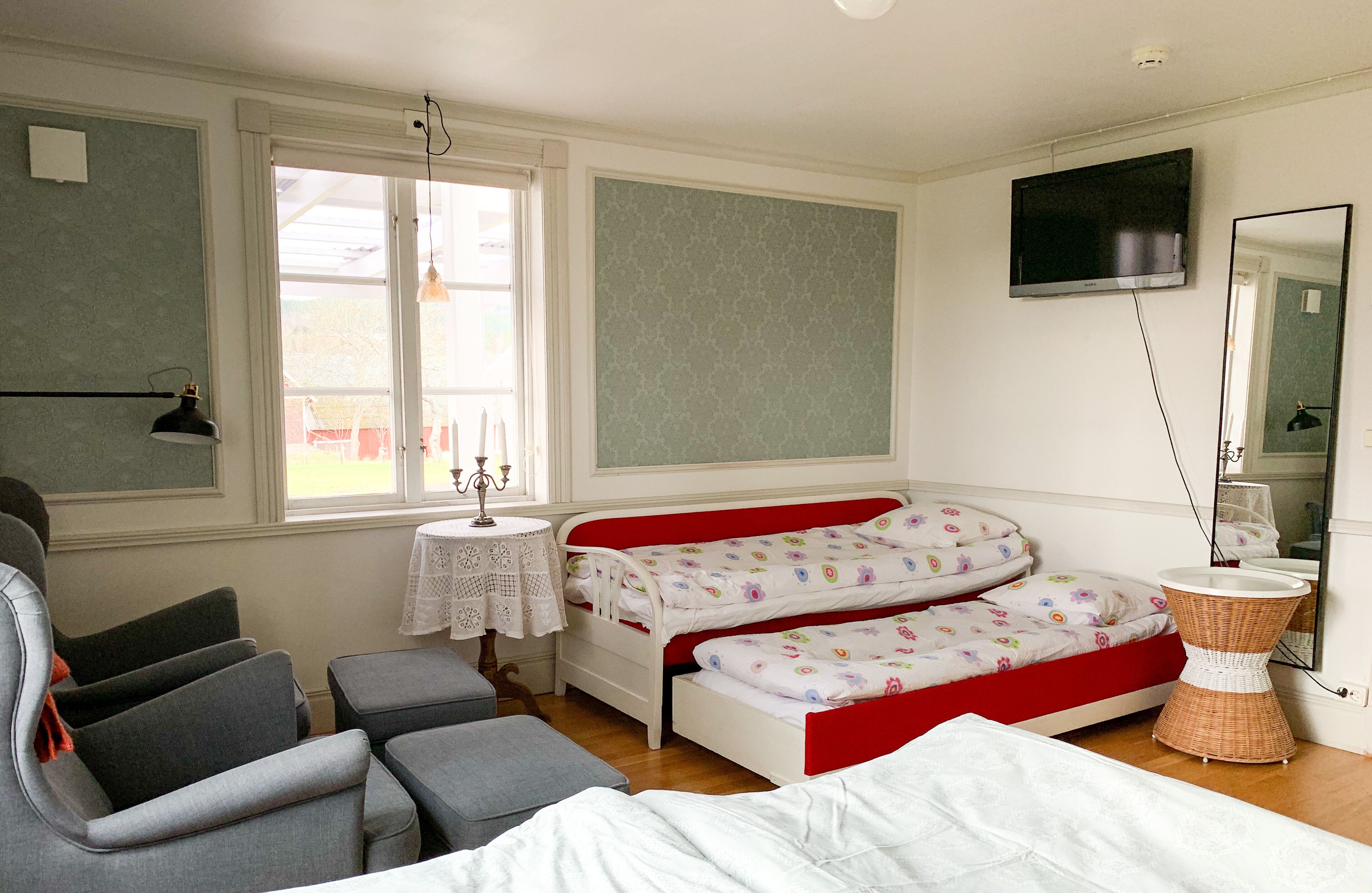 Un dormitorio con dos camas individuales, un televisor, un espejo, una mesita y una silla.