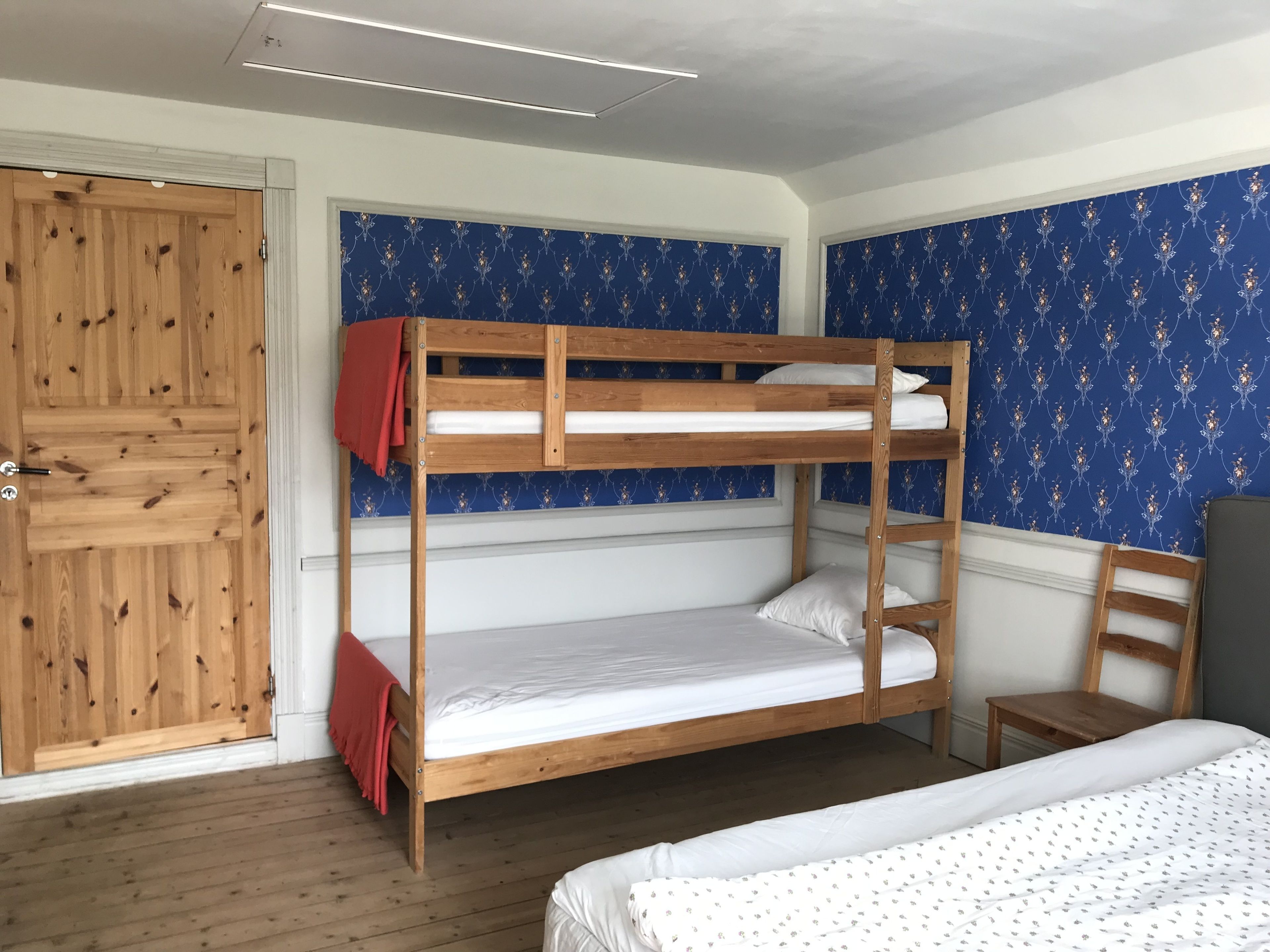 Quarto com beliche, paredes de madeira, guarda-roupa e uma cadeira.