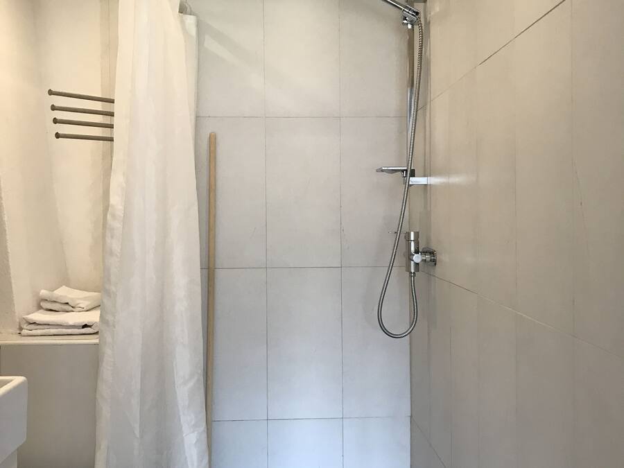 A small, modern bathroom with a shower, toilet, and a towel rack.