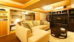 A living room with a sectional sofa, a TV, and a small table. - Winbell Okinawa Nago Coral View (Nago)