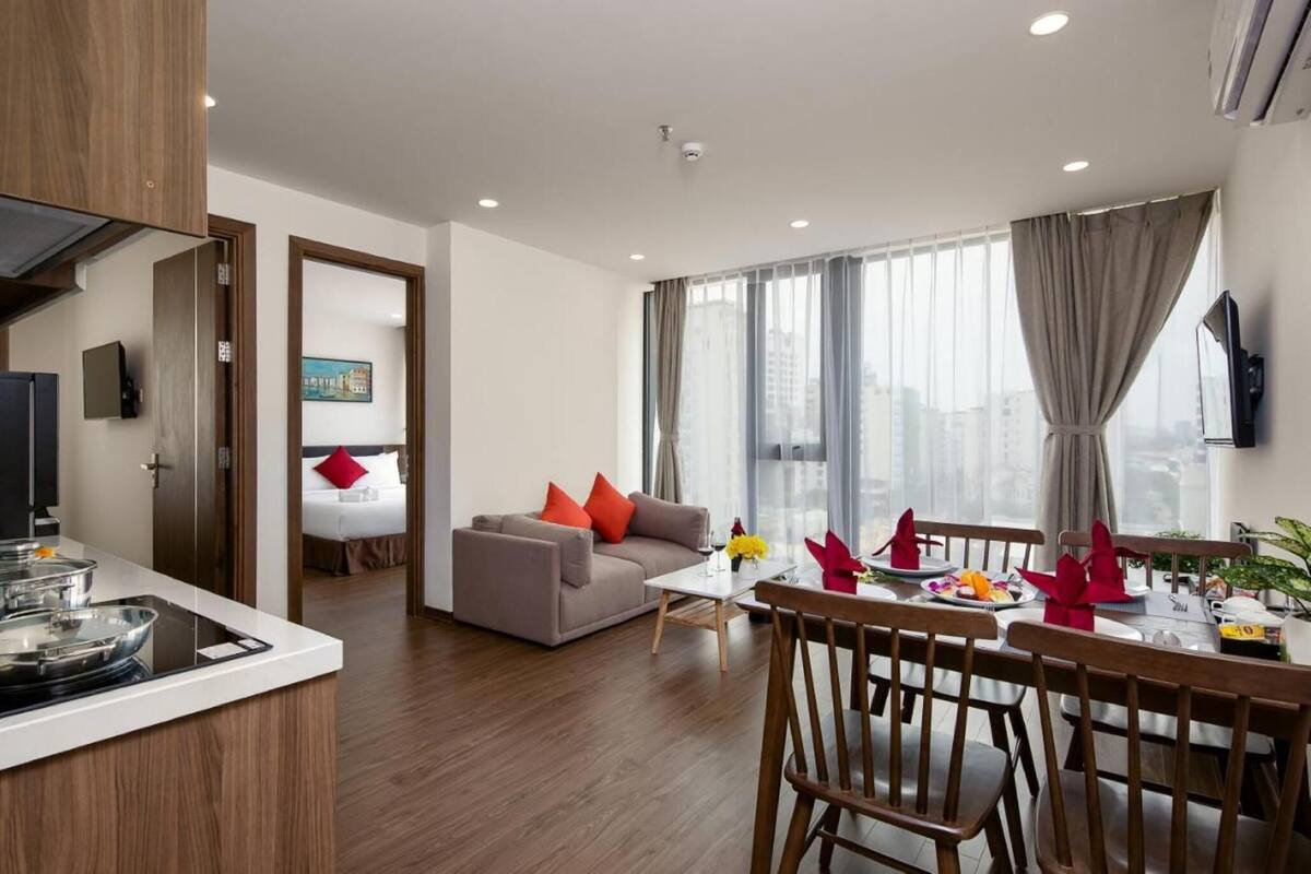 Une chambre d’hôtel moderne dotée d’un coin repas, d’un canapé, d’une télévision et d’une grande fenêtre avec des rideaux.