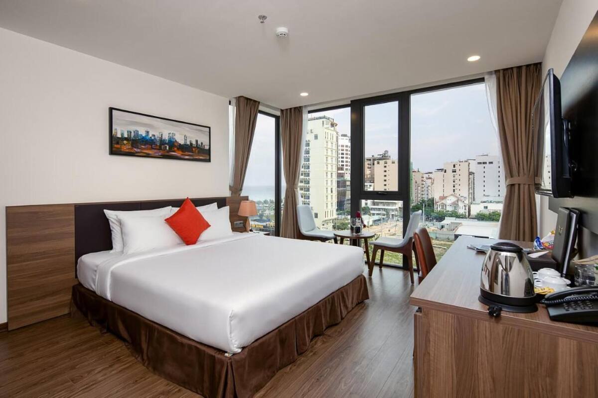 Une chambre d’hôtel avec un grand lit, un bureau avec une bouilloire, une chaise et une télévision.