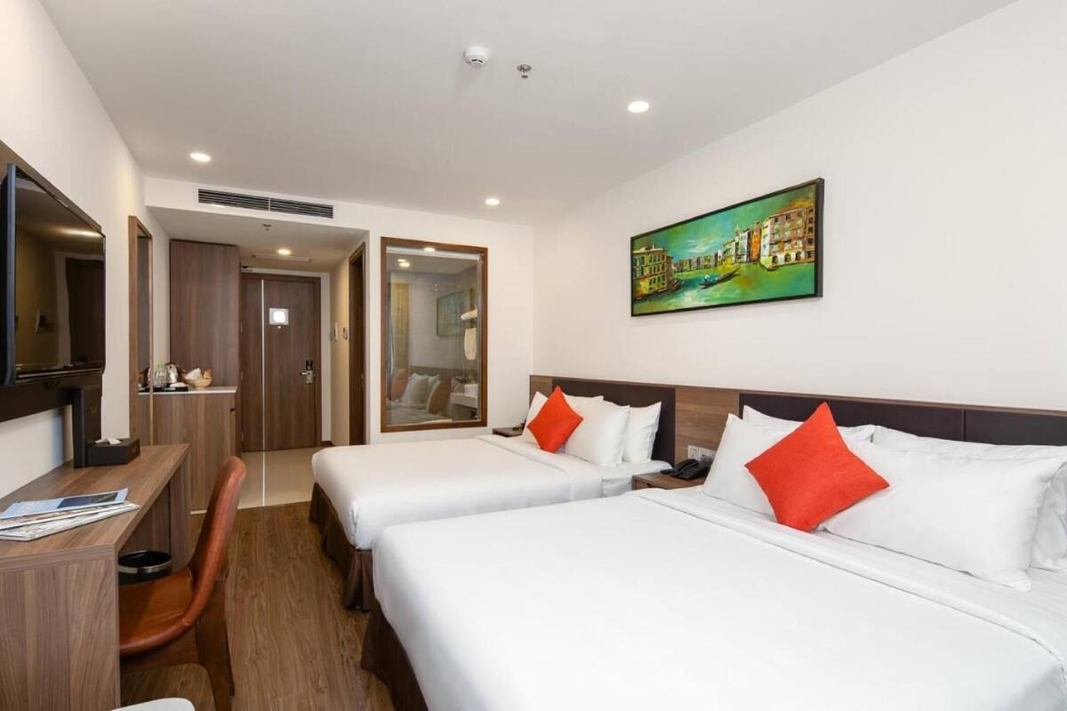 Une chambre d’hôtel avec deux lits, un bureau, une chaise et un tableau au mur.