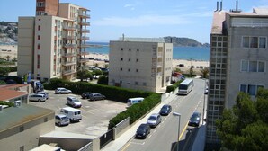 Zona costera urbana con edificios de varios pisos, un estacionamiento y una playa al fondo.