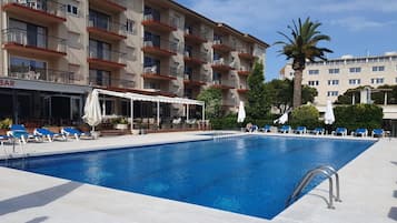 Una piscina al aire libre de temporada, sombrillas