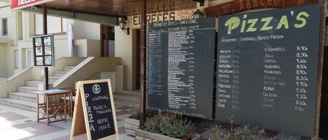 A snack bar named 'Rancho' with a menu board listing various food items and prices.