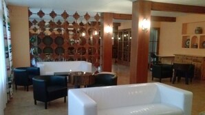 Un vestíbulo espacioso con un sofá blanco, sillones oscuros y una pared de azulejos con diseños decorativos.