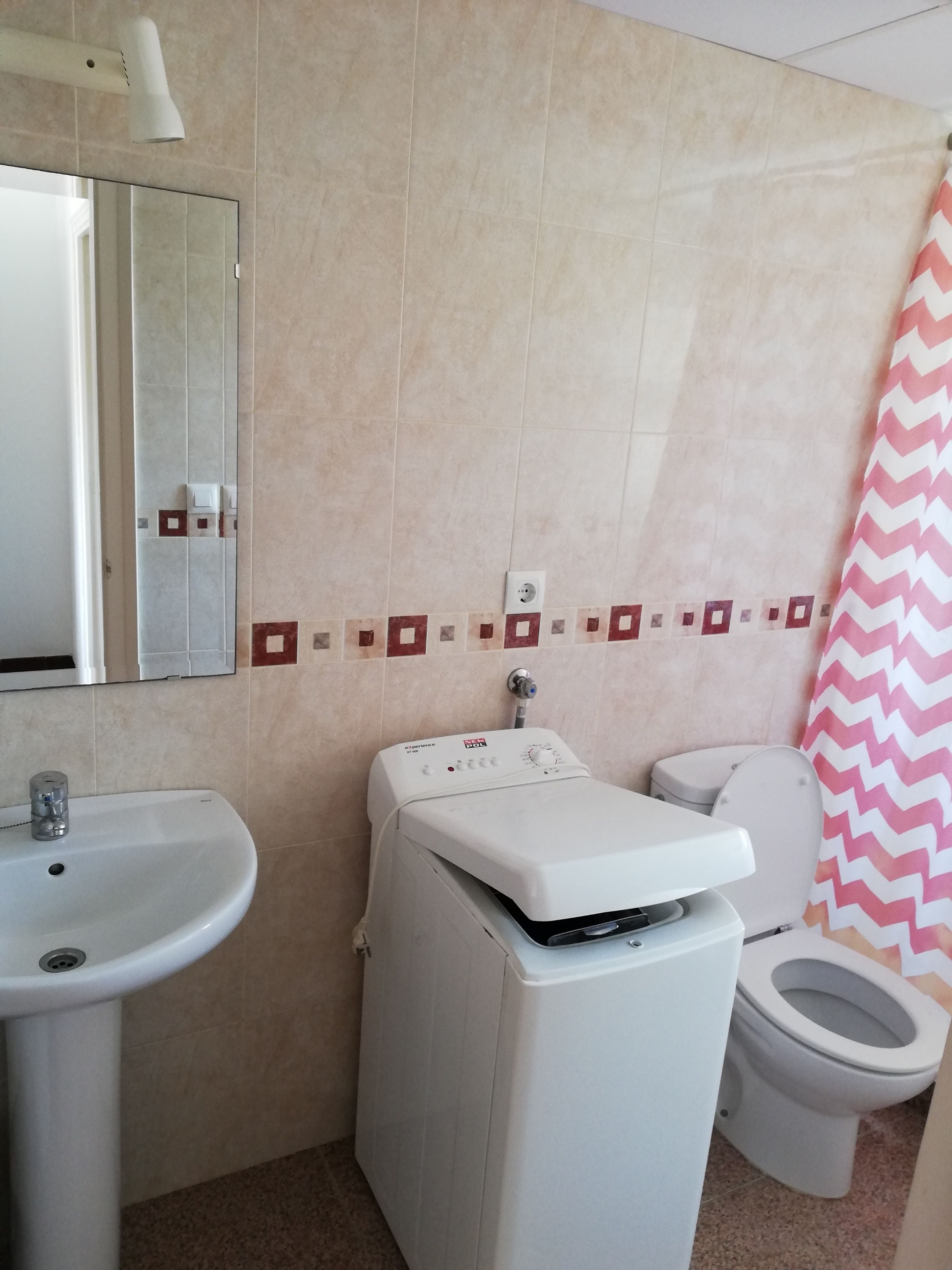 A bathroom with a sink, toilet, and a washing machine.