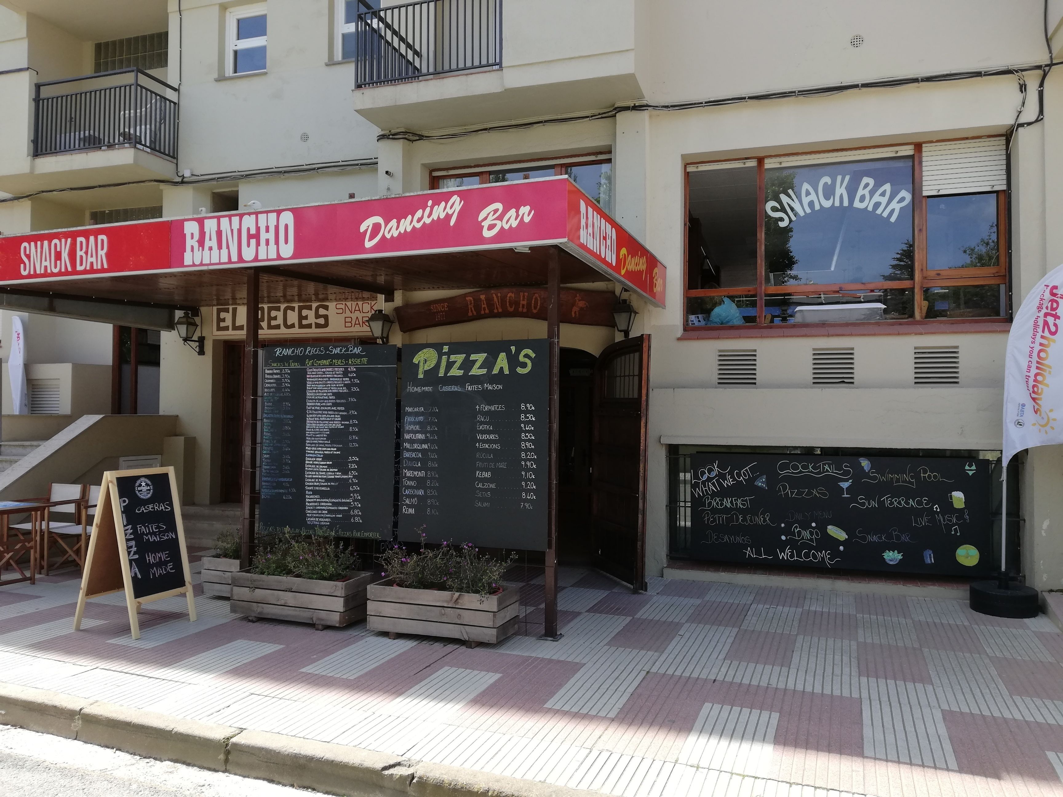 Ein Imbissstand und ein Pizza-Restaurant mit Außenbereich und Speisekarte.