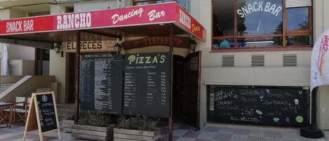 Ein Imbissstand und ein Pizza-Restaurant mit Außenbereich und Speisekarte.