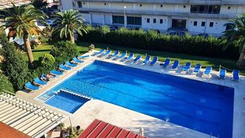 Una piscina al aire libre de temporada, sombrillas
