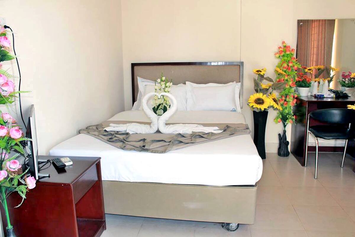 Ein Hotelzimmer mit Bett, Schreibtisch, Stuhl und Fernseher.