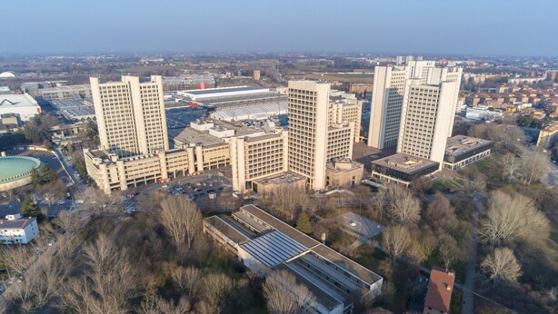 An aerial view of a cityscape with modern buildings, a large stadium, and surrounding greenery. - Bologna Fiera Guest House (Bologna)