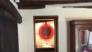 Un estrecho acceso que da a un baño con suelo de baldosas, un lavamanos y un espejo.