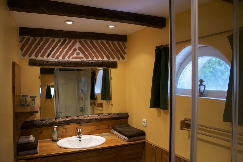 A bathroom with a wooden vanity, a white sink, a mirror, and a window with a view of greenery.