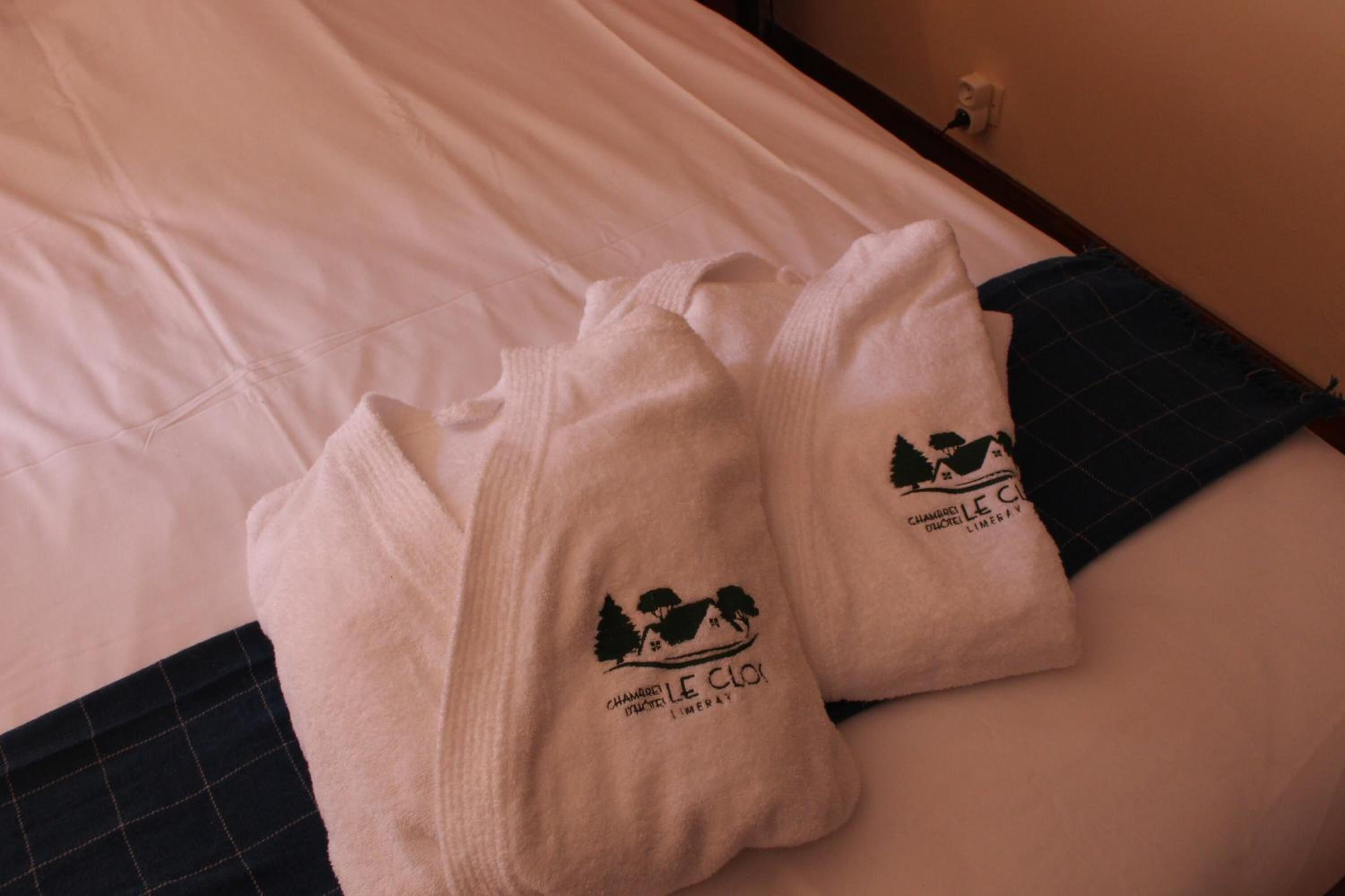 A bed with a white sheet and two folded towels with a logo and text on them.