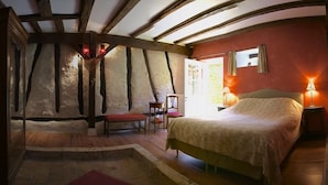 Un dormitorio acogedor con cama, una silla, una mesita y un espejo.