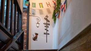 A staircase with a wall-mounted sign indicating directions to various rooms and locations within the building. - Sip N' Camp - Hostel (Bangkok)
