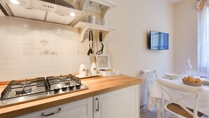 A modern kitchen with a gas stove, white cabinets, and a dining area with a table set for two.